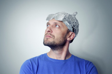 Bearded funny man in a cap of aluminum foil. Concept art phobias