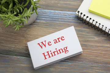 We are Hiring. Office desk table with business card, pen and flower. Top view. 