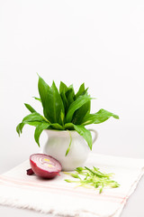 Still life composition with bear's garlic (Allium Ursinum) leaves and buds and sliced onion