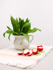 Still life composition with bear's garlic (Allium Ursinum) leaves and buds and radishes