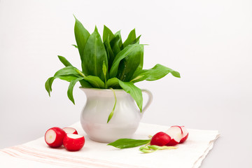 Still life composition with bear's garlic (Allium Ursinum) leaves and buds and radishes