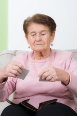 seniorin schaut auf ihre kreditkarten