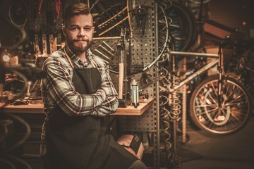 Fototapeta na wymiar Stylish bicycle mechanic standing in his workshop.