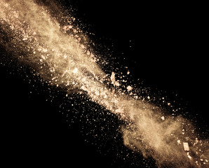 Explosion of brown powder on black background