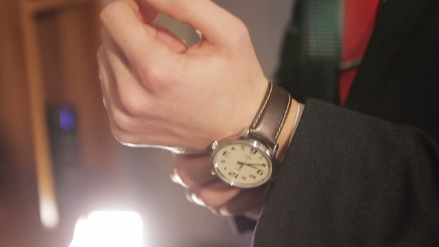 Male businessman puts his hand on the clock