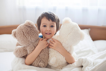 Cute child with teddy bears, lying in bed, looking at camera