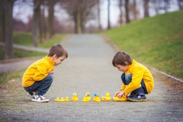 Two adorable children, boy brothers, playing in park with rubber