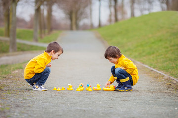 Two adorable children, boy brothers, playing in park with rubber