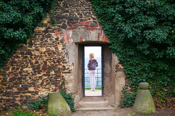 girl standing in the doorway of a stone wall covered with greenery © stock.film