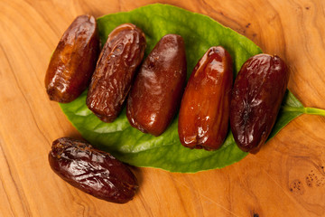 Sweet dried dates fruit on green leaf, mediterranean desert on w