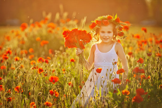 Little girl in poppy field on sunset. Soft focus. Smiling girl.