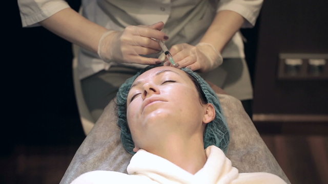 A woman is getting a mesotherapy of her face