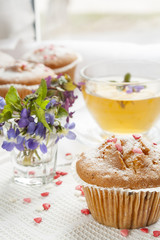 Tasty muffins with sugar hearts and cup of green tea
