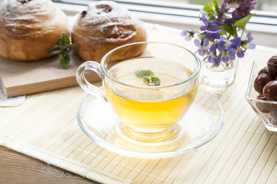 Cup of green tea with lemon balm and tasty rolls
