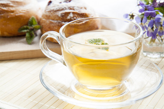 Cup of green tea with lemon balm and tasty rolls