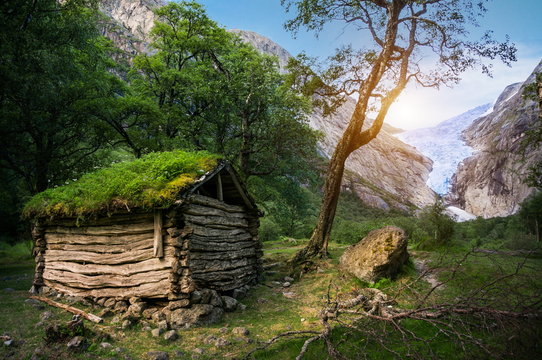 Norwegian typical grass roof wooden old house and Briksdal glacier panorama, as in a Magical forest