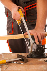 Young carpenter cuts a wooden lath with a saw isolated over whit