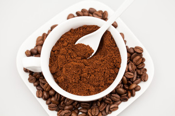 White coffee cup, coffee plate and teaspoon with coffee beans and coffee powder