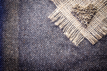 Hemp (cannabis) seeds heart on hemp fabric background