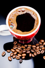 Red cup of coffee with coffee beans and dark background