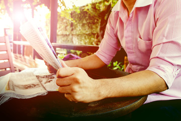 over sunlight, businessman reading a financial newspaper while sitting in coffee shop, over morning light, [blur and selective focus background]