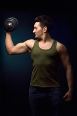 Fototapeta na wymiar Muscle man training with dumbbell on dark background