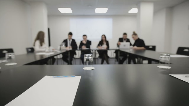Business team at a meeting: Group of business people discussing, documents and ideas. Defocused footage, slider camera movement.