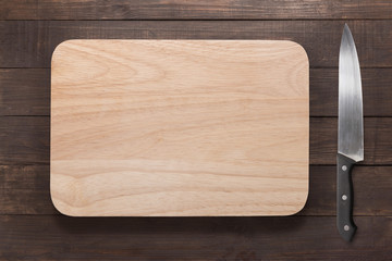 Knife and cutting board on the wooden background