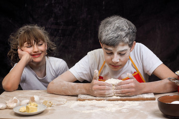 Teens knead the dough. Funny girl and the guy, mired in the flour. Baking Products. Cookware....