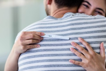 Happy couple hugging with positive pregnancy test