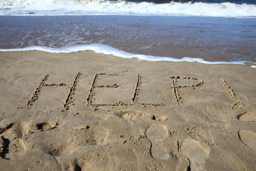 help/ words written in the sand on a beach 