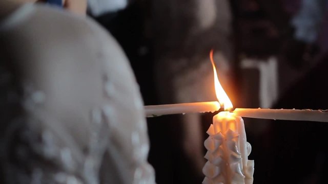 Bride and groom are holding a burning candle