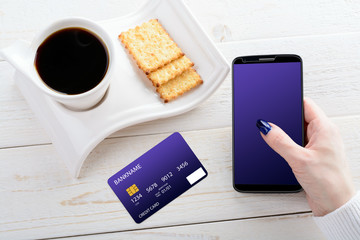 Woman sitting at table and pays the purchase through smartphone
