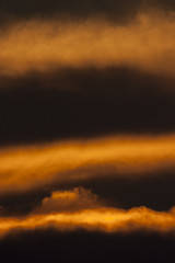 Franjas de nubes iluminadas en el cielo oscuro del atardecer