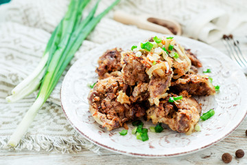 Fried chicken liver with green onion and spices on a wooden background