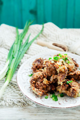 Fried chicken liver with green onion and spices on a wooden background