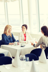 women drinking coffee and talking at restaurant