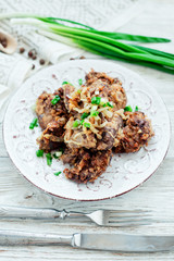 Fried chicken liver with green onion and spices on a wooden background