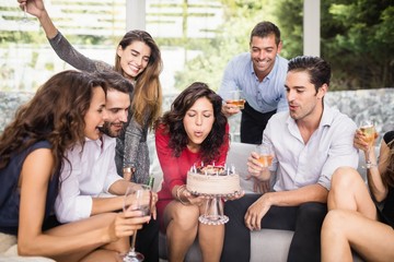 Woman blowing birthday candles with friends
