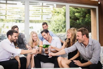 Naklejka premium Man pouring champagne in glasses for friends