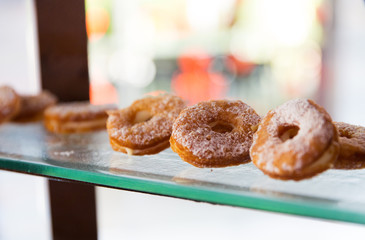 close up of sugared donuts on showcase shelf