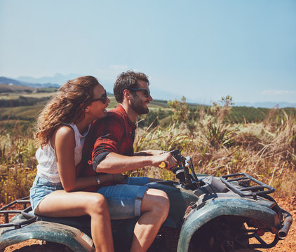 Couple driving off-road with quad bike
