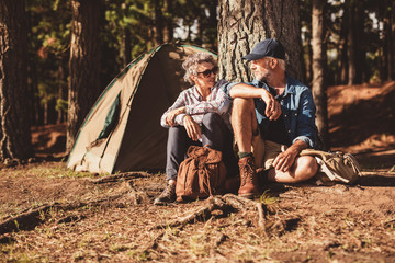 Happy senior couple camping in forest