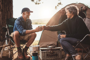 Mature couple with coffee camping by a lake