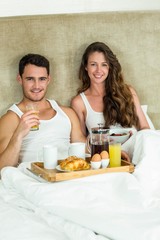 Obraz na płótnie Canvas Young couple having breakfast on bed