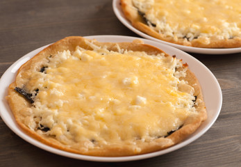 Pizza with cheese in a white plate on wooden table