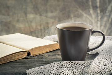 Cup of black coffee with milk  in front of the window in the morning. Selective focus on cup.