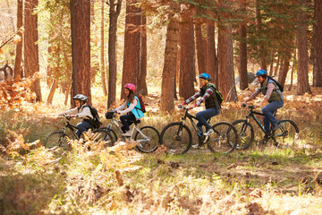 Obraz premium Family mountain biking on forest trail, California