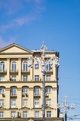 Old building face with stucco molding and street lamps before against blue sky background. Moscow, Russia. 
