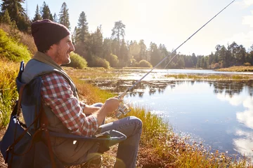 Fototapeten Man relaxing and fishing by lakeside, California, USA © Monkey Business